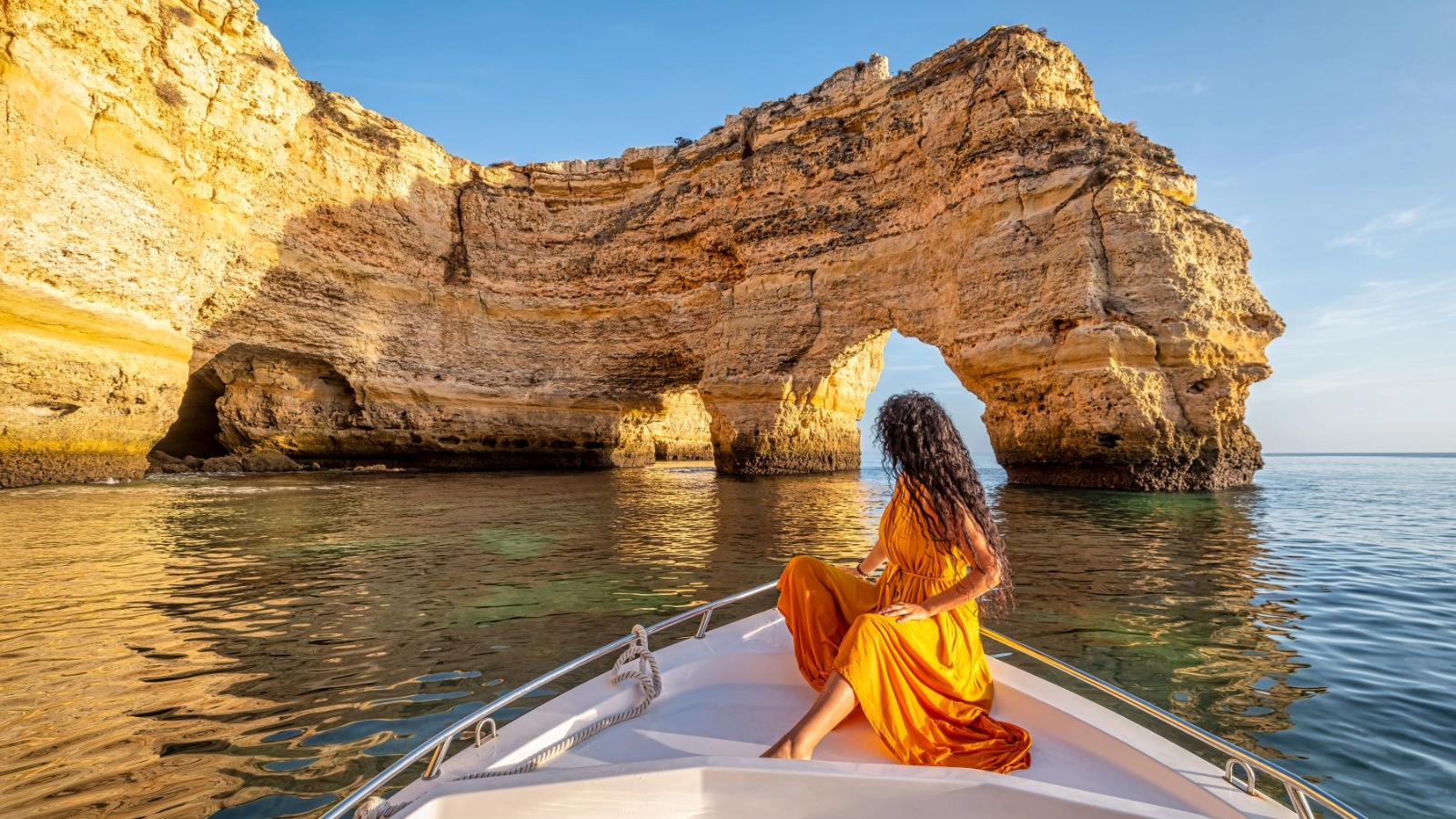 Woman on Boat Admiring Arch at Praia da Marinha, Portugal