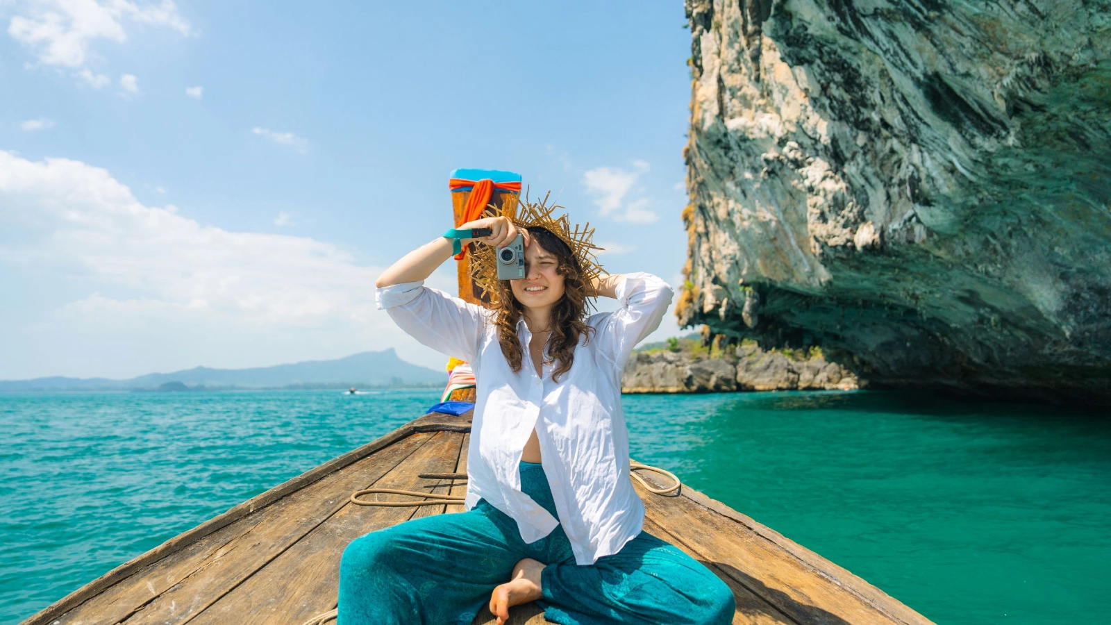 A person taking a photo while seated on a traditional Thai long-tail boat in the Andaman Sea