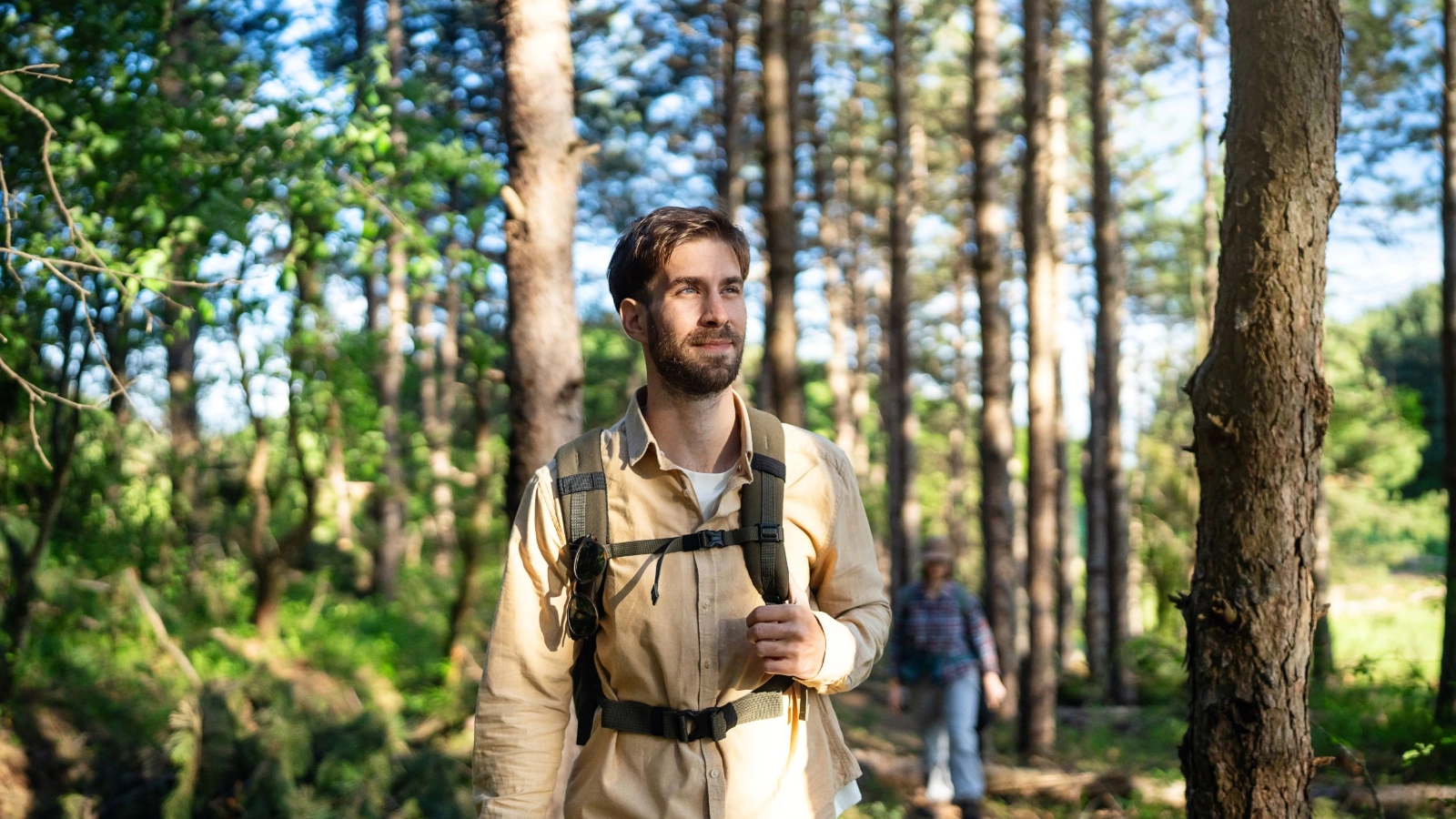 Man hiking through a sunlit forest with a backpack