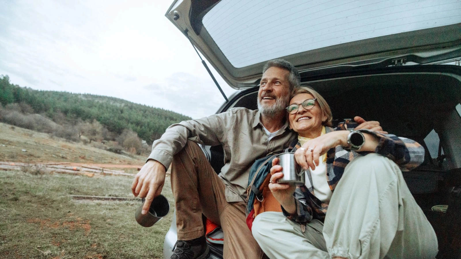 Active mature couple having a warm drink after hike in nature.