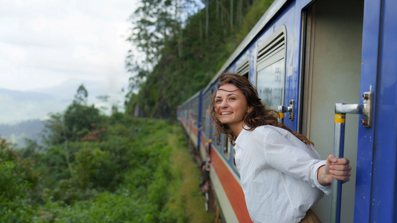 Woman looking out of train door traveling in Sri Lanka