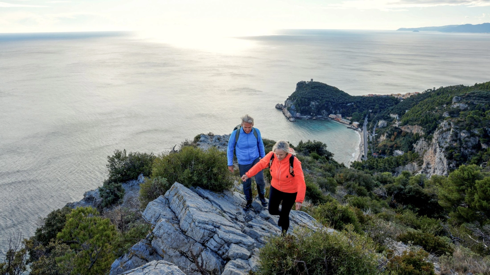 Mature couple hike on ridge above sea, winter, Liguria