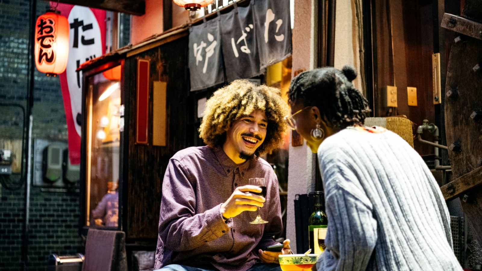 Couple laughing with wine outside Japanese restaurant