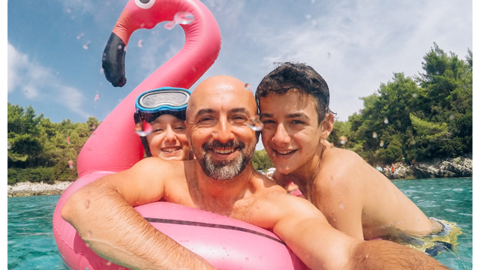 A father and his children taking a selfie with a pink inflatable flamingo float