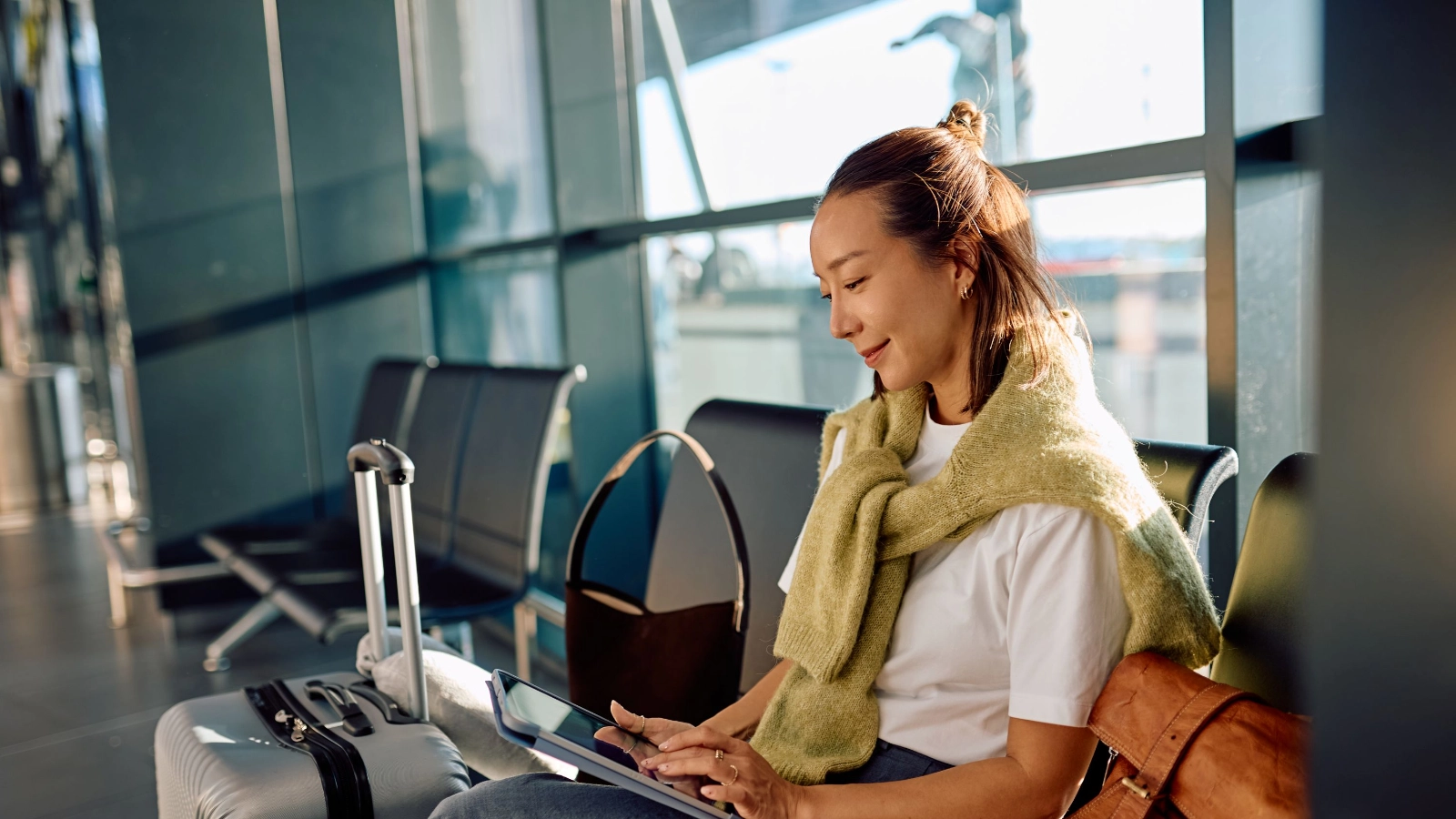 Woman using tablet waiting at airport terminal