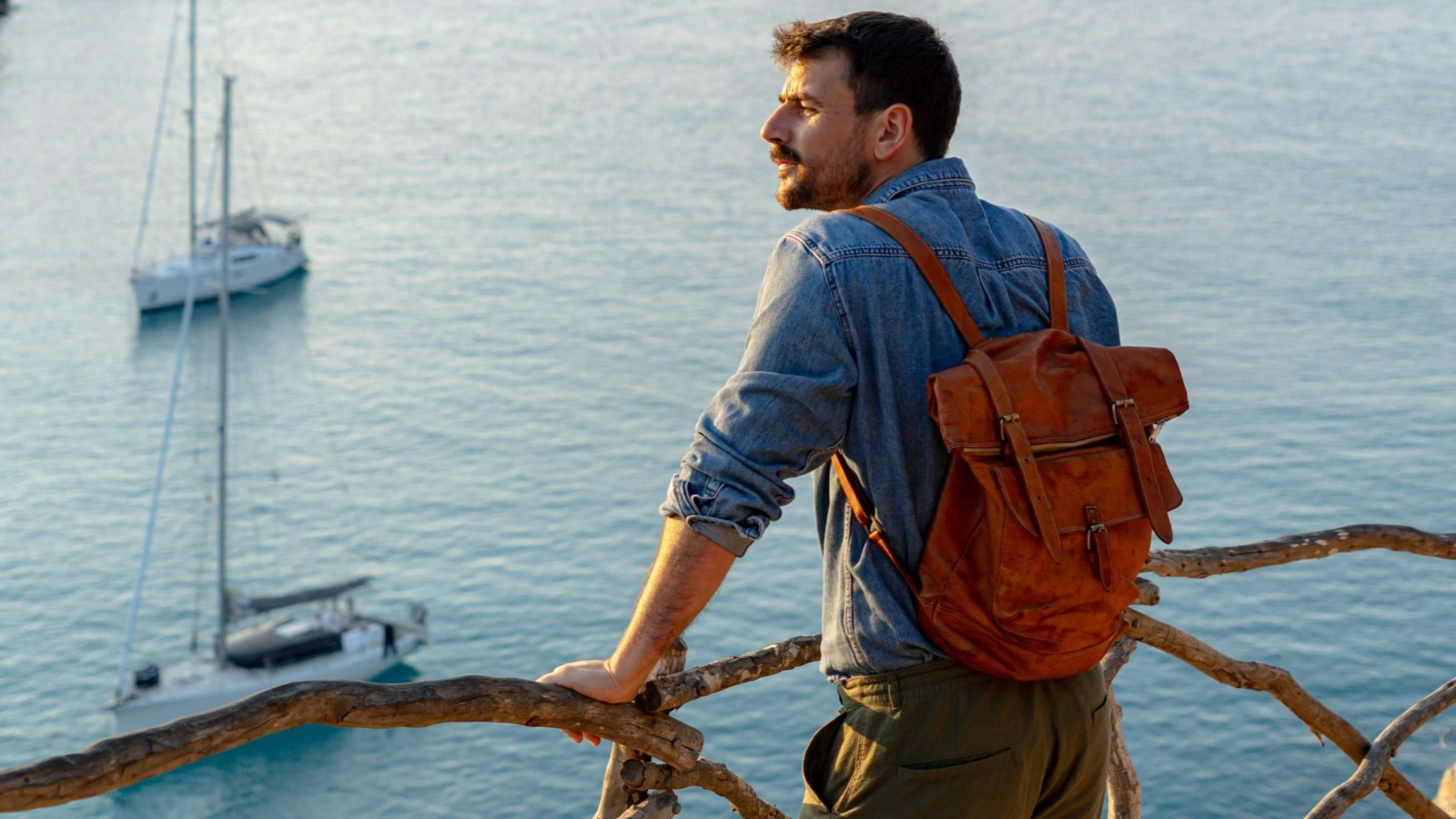 Tourist enjoying breathtaking mediterranean seascape with sailboats at sunset
