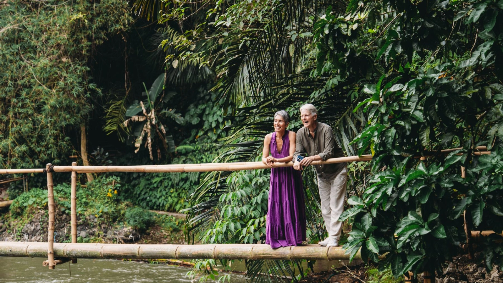 Senior couple traveling on bamboo bridge over tropical river