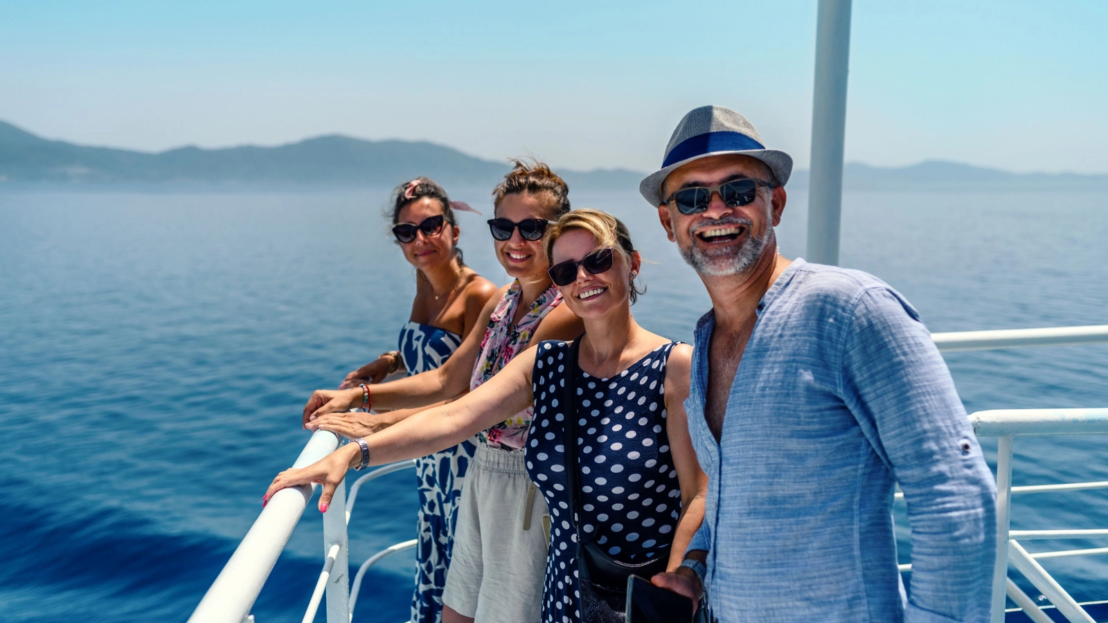 Group of friends on the ferry boat deck on a sunny day traveling on vacation