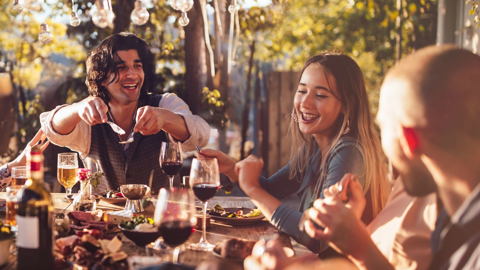 Young multi-ethnic friends dining at rustic countryside restaurant at sunset