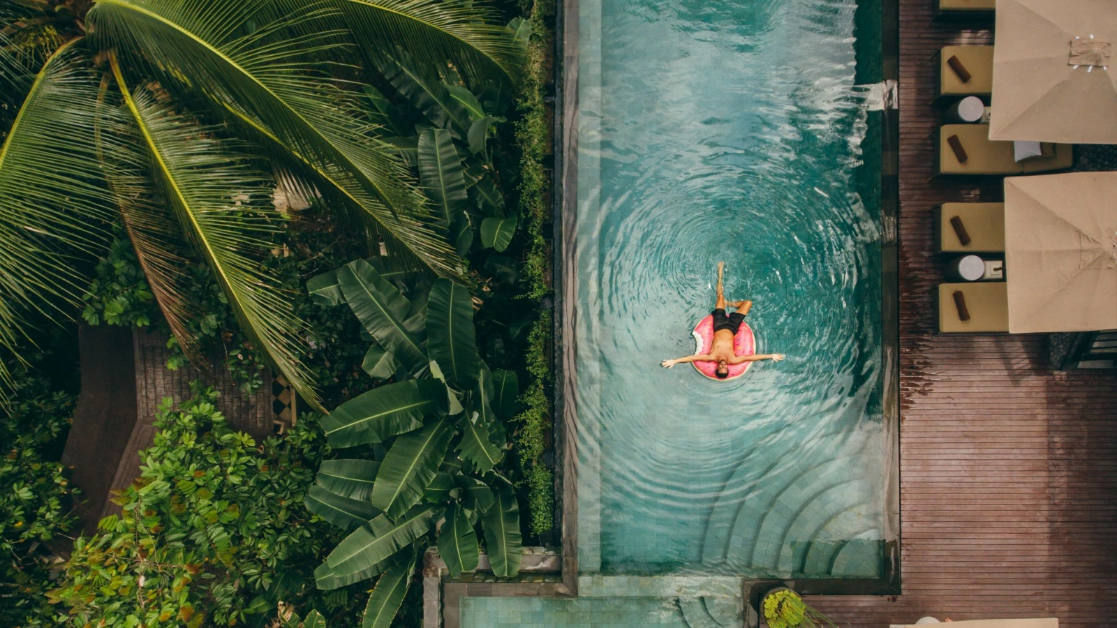 Luxury resort with man on inflatable ring in pool