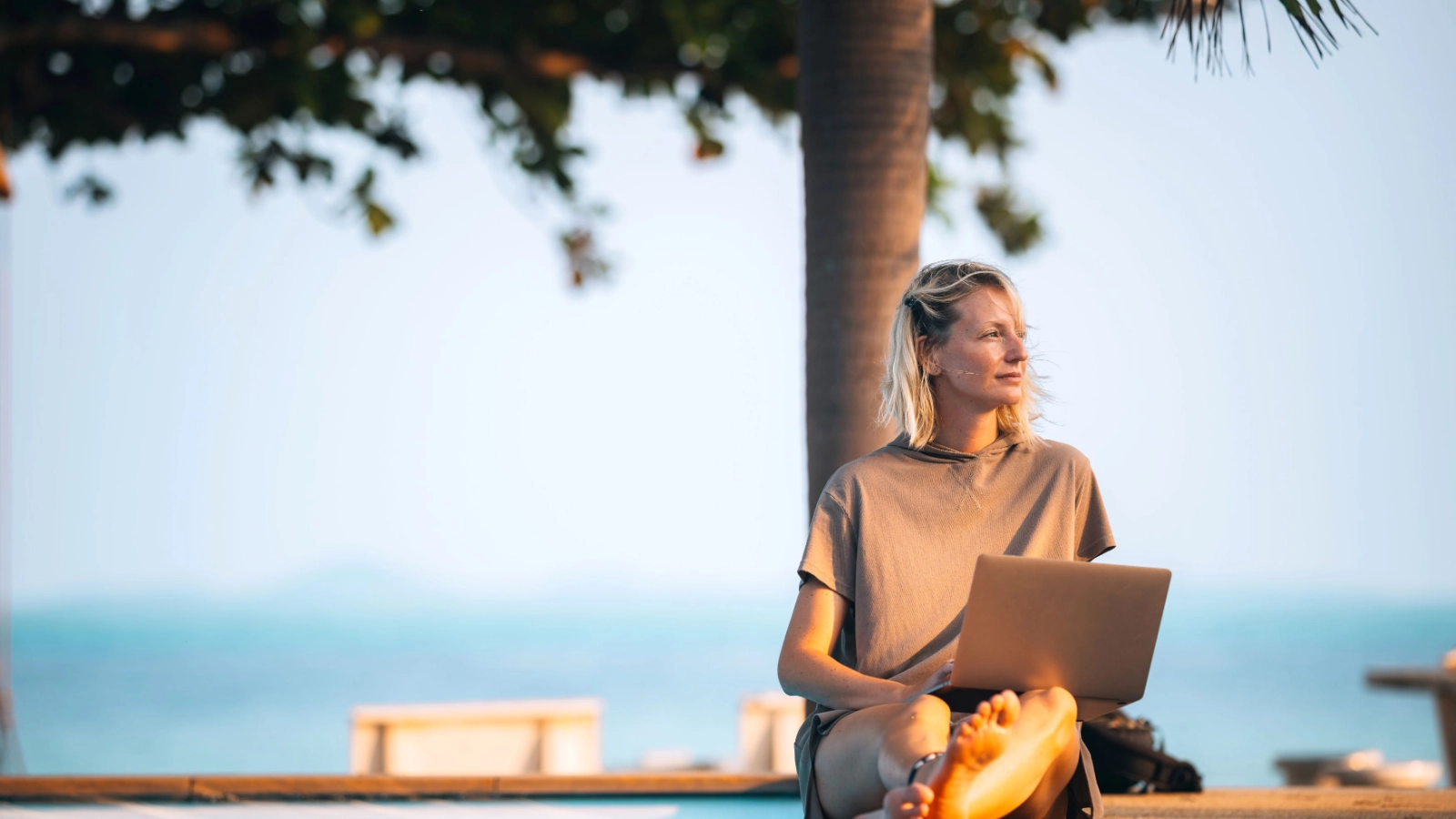 A woman works remotely by the pool