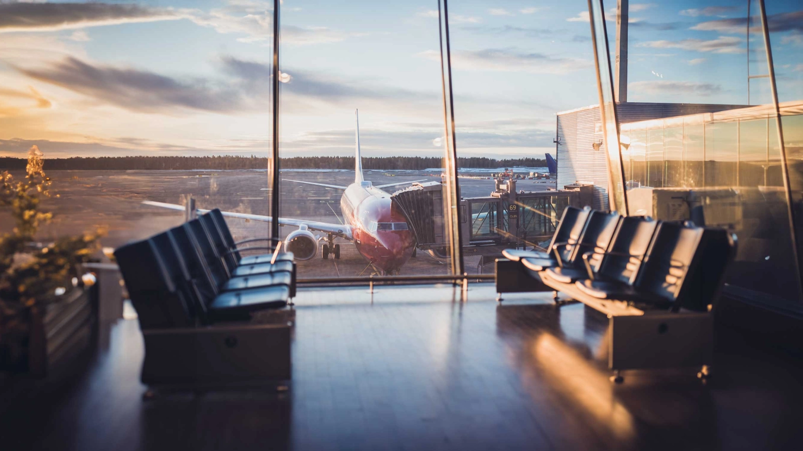 An airplane parked at the gate outside large windows of an airport depature lounge