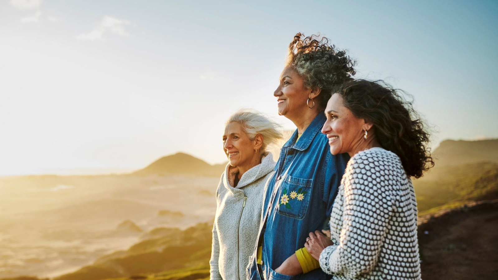 Smiling mature friends standing by a scenic coast during a road trip