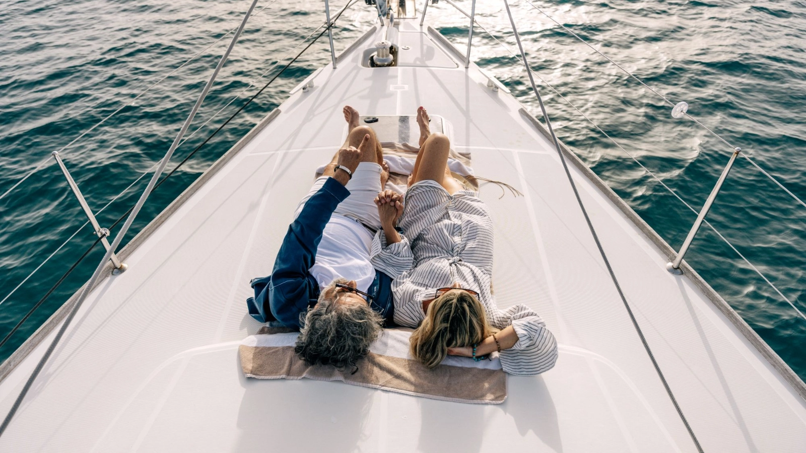 Couple relaxing on sailboat deck holding hands