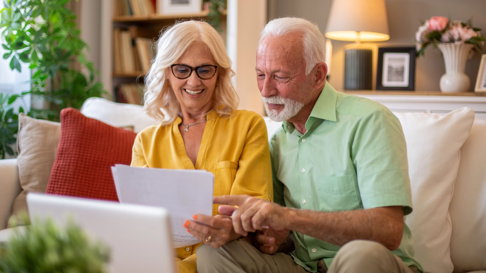 A couple sat on a white sofa reviewing insurance documents