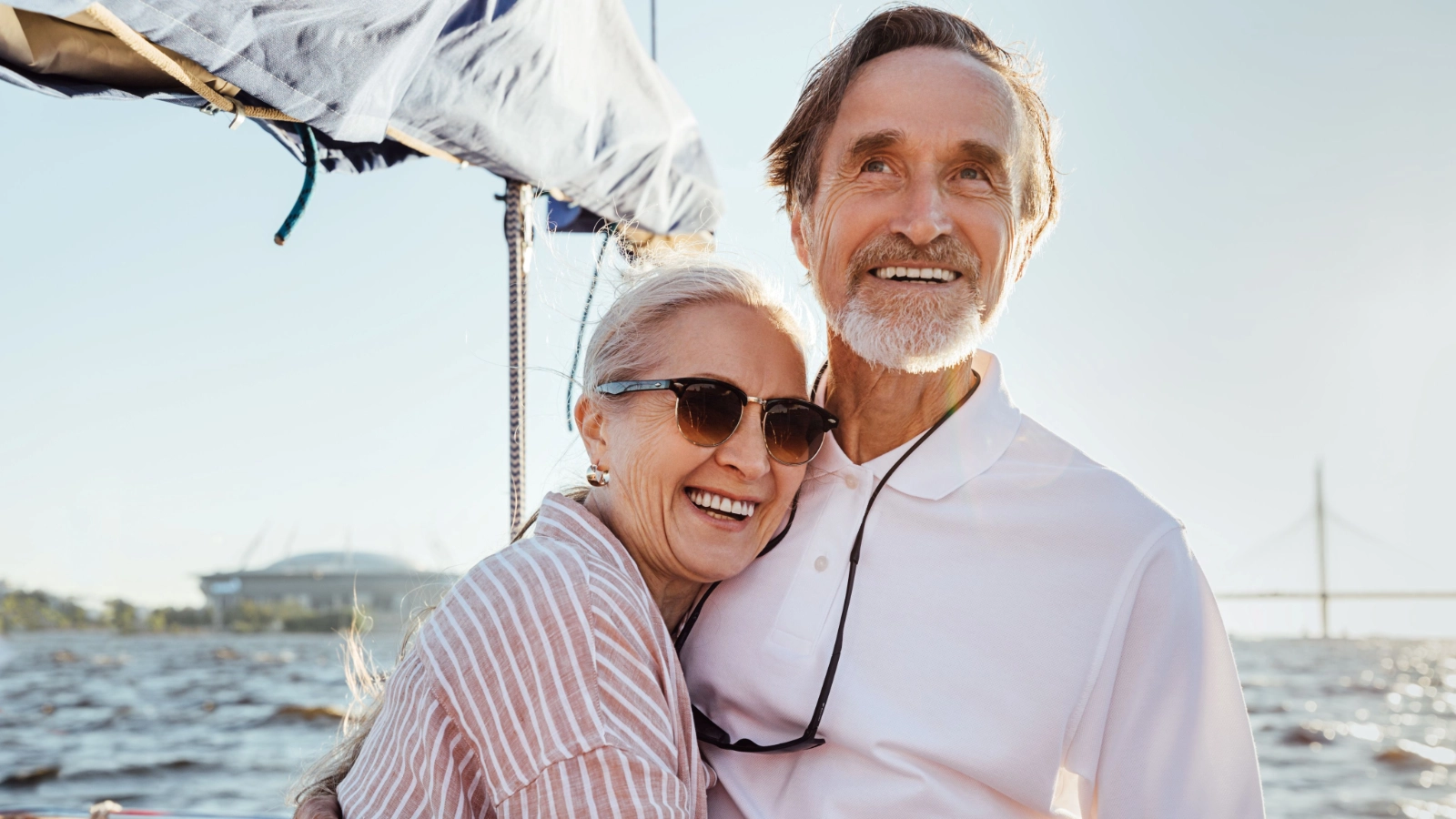 A happy mature couple enjoying a scenic sailing trip on a bright, sunny day.