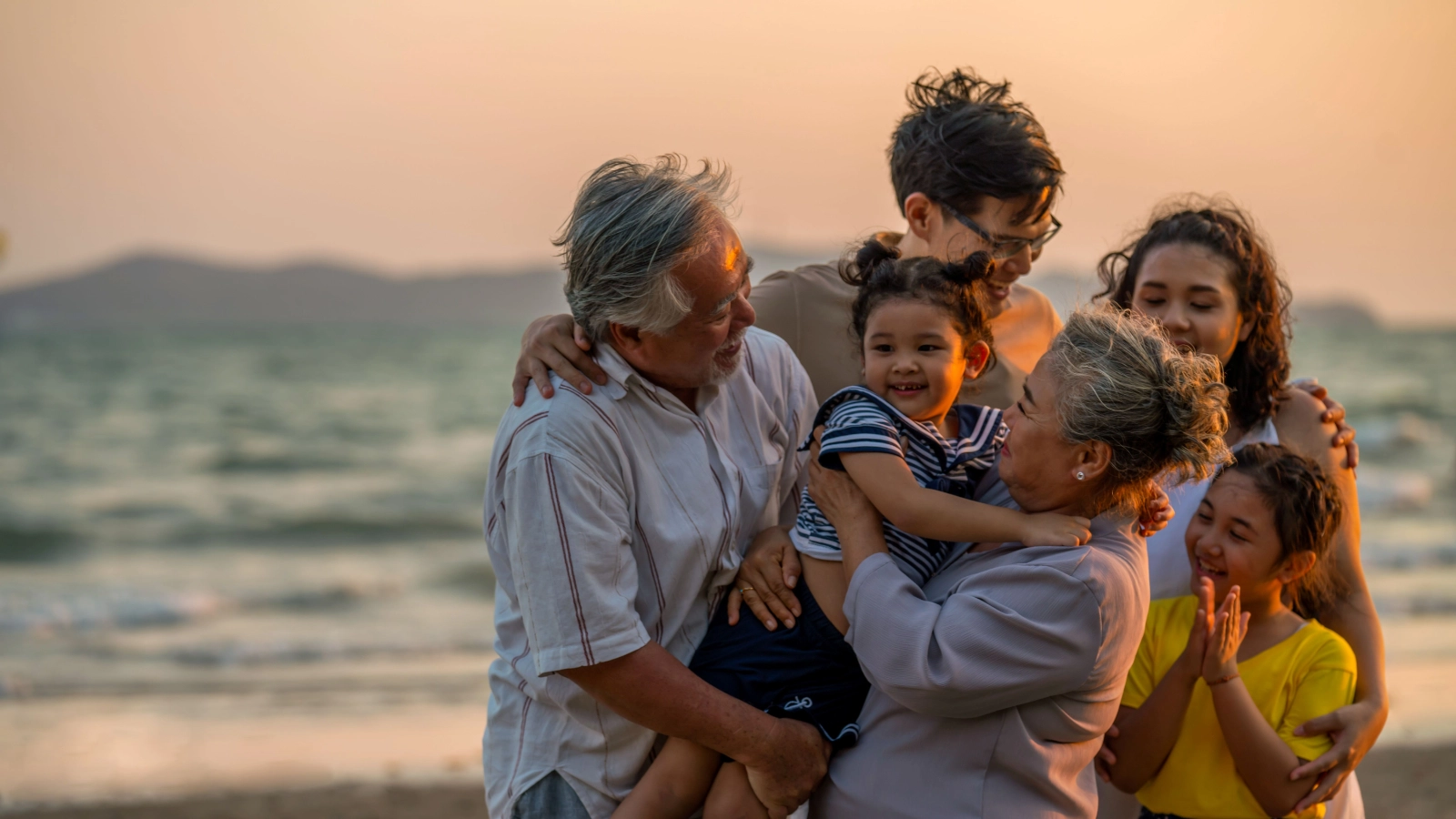 A multi-generation family enjoying the beach at sunset