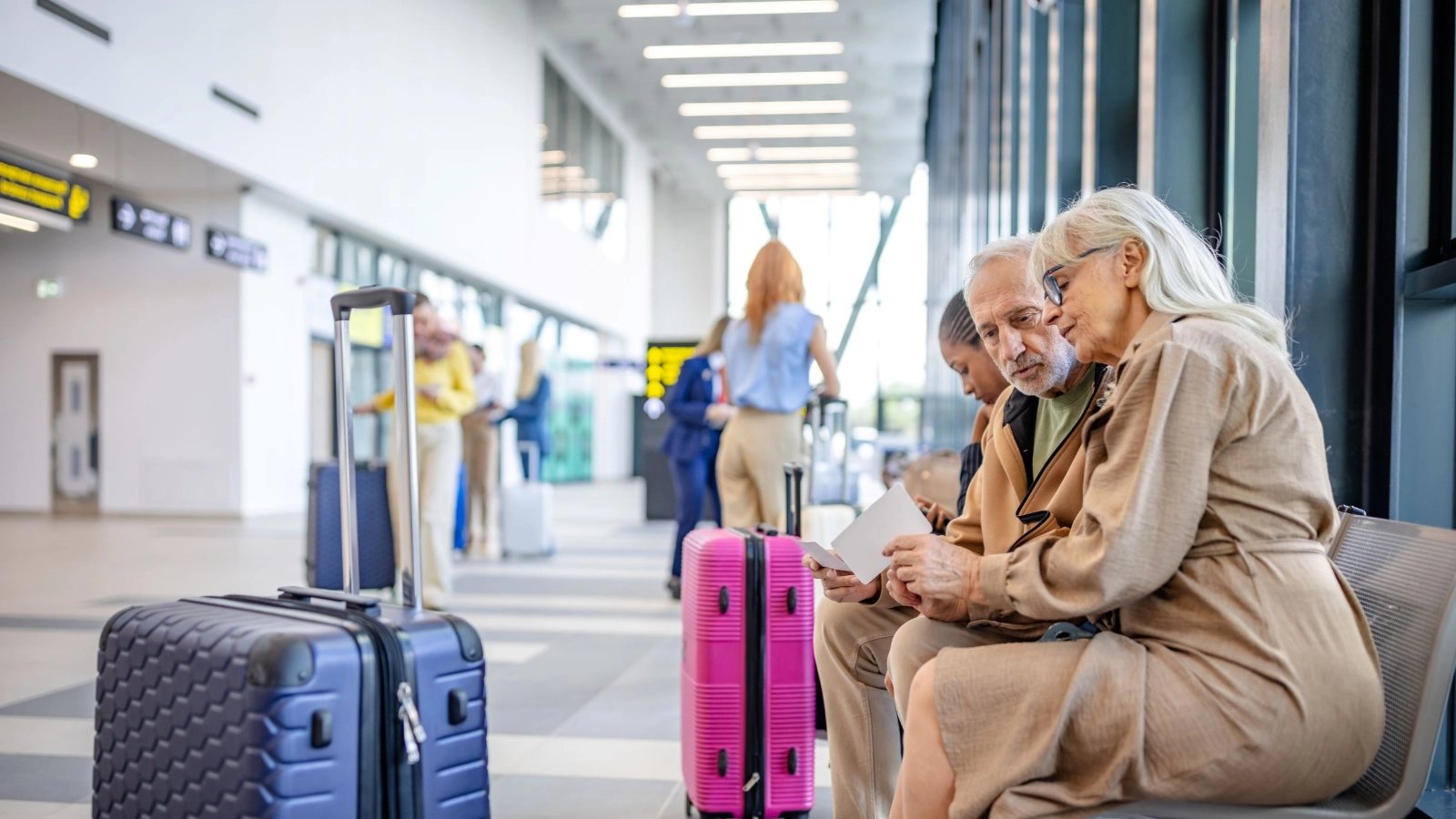  Elderly couple sitting with luggage in airport terminal
