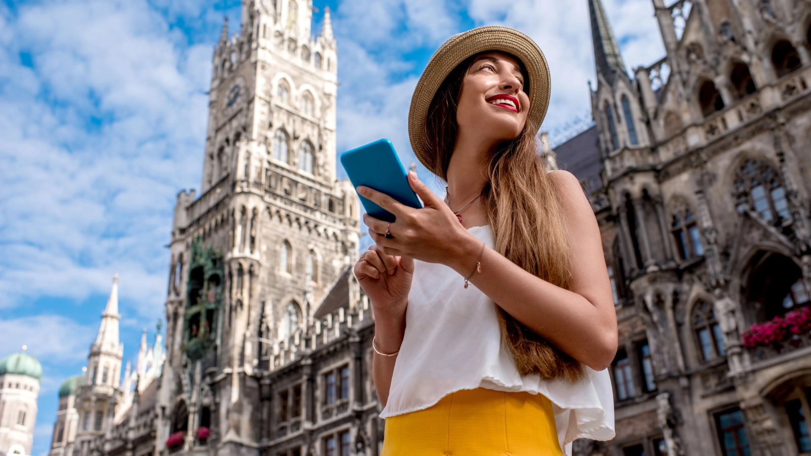 Female tourist using mobile phone on the central square in front of the famous town hall building in Munich