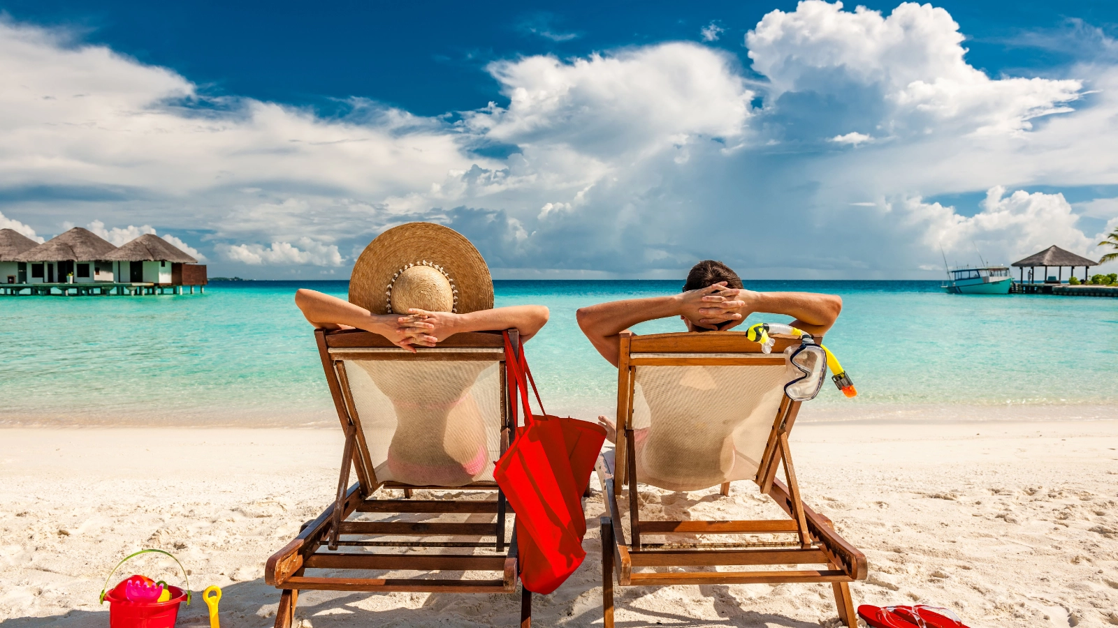 Two people relaxing on lounge chairs on a tropical beach