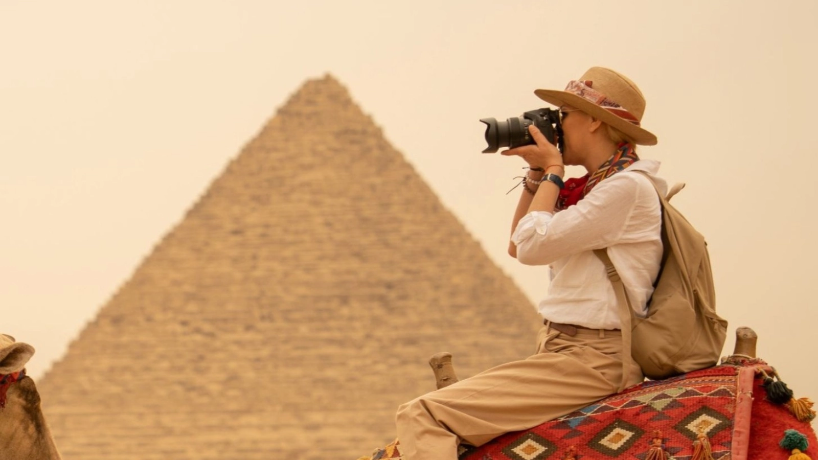 Adventurous tourists riding camels taking a photograph