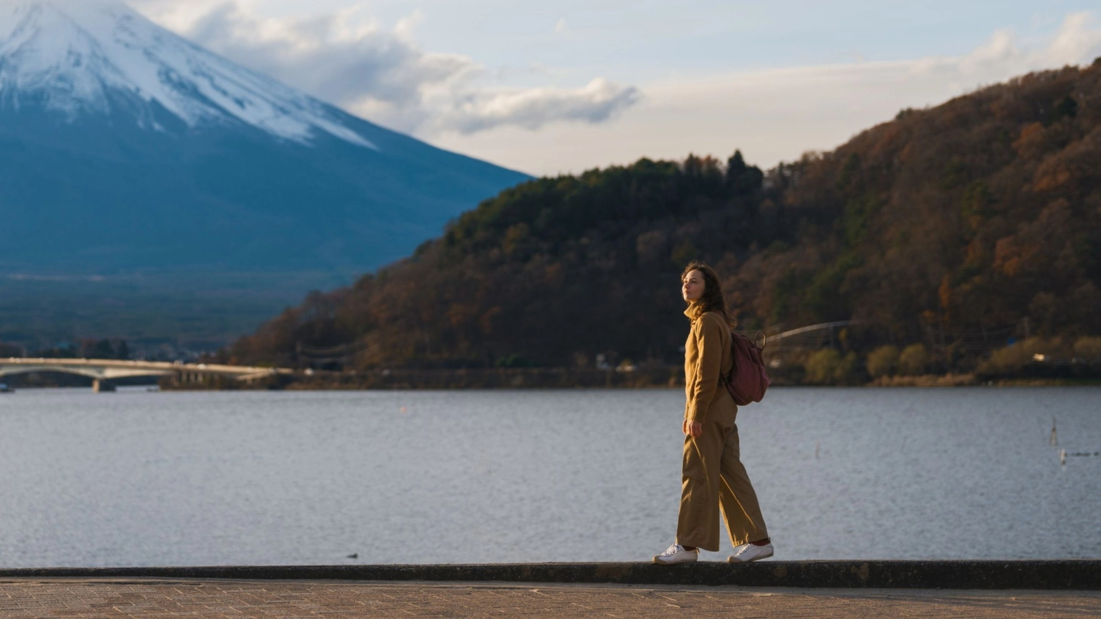 Woman walking at the shore of Kawaguchiko lake in Japan overlooking Fuji mountain
