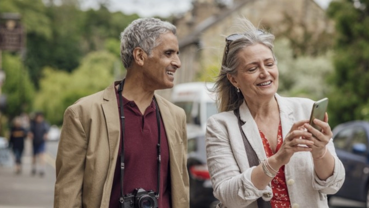 an image of a couple looking at a phone while walking in the road