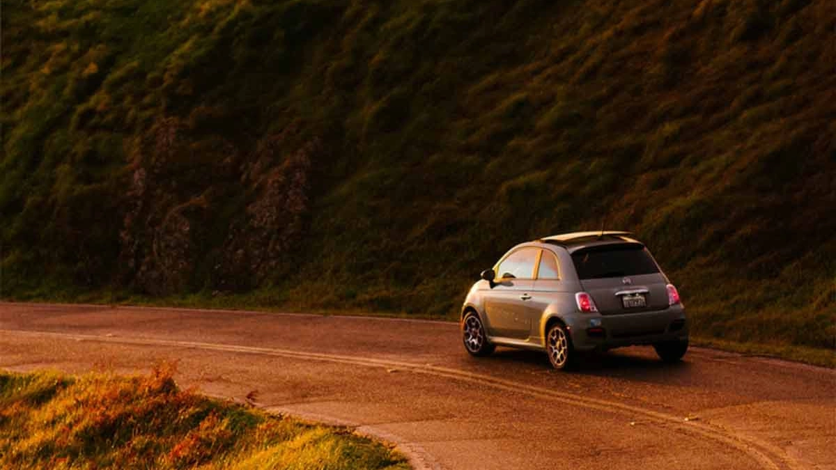 A Fiat 500 driving along a country road