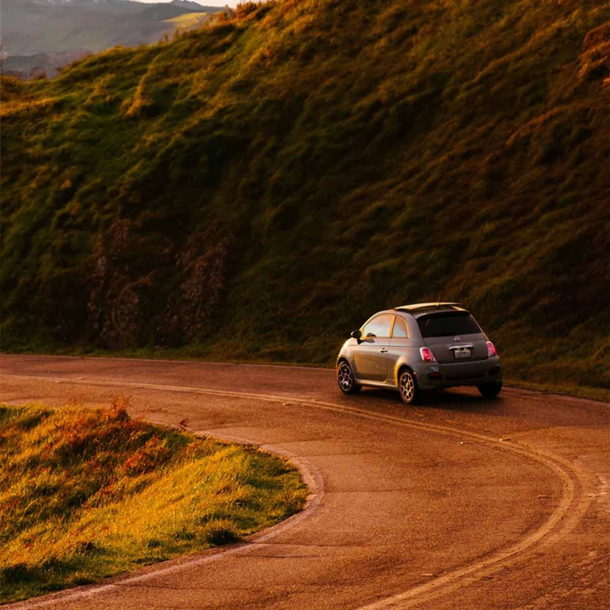 A Fiat 500 driving along a country road